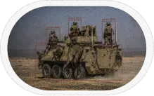 Armored military vehicle with multiple turrets on desert terrain where custom computer vision system is deployed